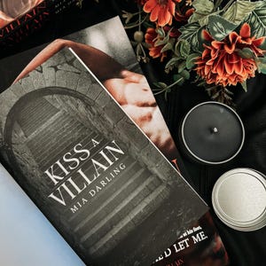 May include: A book titled "Kiss a Villain" by Mia Darling with a black and white photo of a stone archway and stairs on the cover.