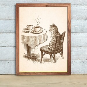 May include: A framed print featuring a detailed pen and ink illustration. A cat sits on a chair, gazing at a table set with a cup of coffee, creamer, and a spoon. The artwork has a vintage, cafe theme.