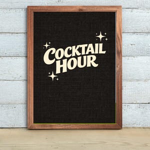May include: A framed sign with the words "COCKTAIL HOUR" in a retro font. The text is cream-colored against a black background. The frame is a dark wood color, and there are starburst graphics on the sign.