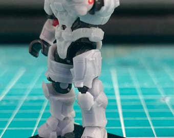 May include: A white and gray action figure of a soldier wearing armor and a helmet. The figure is standing on a black base.