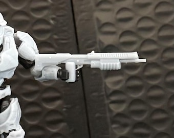 May include: A light gray toy shotgun held by a white action figure. The toy gun has a pump-action design with a ribbed handguard and a long barrel. The figure is wearing white armor and is posed against a dark background.
