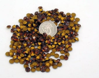 May include: A large pile of gold and brown rhinestones, with a US dime for scale.