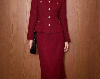 May include: A red tweed skirt suit with a round-neck jacket and a knee-length pencil skirt. The jacket features pearl-like buttons. A black handbag is held in the hand.