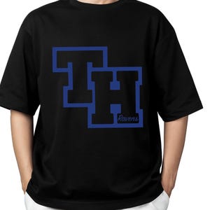 May include: Black t-shirt featuring a blue graphic of the letters "TH" stacked, with the word "Ravens" below. The letters have a blue outline and a black fill. The shirt is a crew neck style.