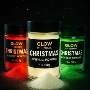 Puede incluir: Tres botes de polvo acrílico que brillan en la oscuridad en rojo, blanco y verde. Cada bote tiene una tapa negra y una etiqueta que dice "Glow Christmas Acrylic Powder 2 oz/30g". Un pequeño montón de polvo blanco está delante.