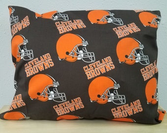May include: A brown pillowcase with a repeating pattern of orange Cleveland Browns football helmets and the words "Cleveland Browns".