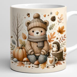 May include: A white ceramic mug featuring a whimsical autumn scene. A teddy bear wearing a hat, scarf, and sweater sits near a pumpkin, mushrooms, and leaves. A hedgehog sits on a tree stump next to a mug of coffee with a heart.