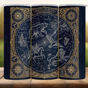 May include: A navy blue tumbler featuring a celestial map design. The design includes constellations, zodiac symbols, and the text "MAPPA CELESTIS". Gold-colored ornate borders and accents frame the design, creating a vintage aesthetic.