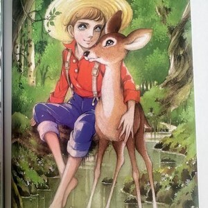May include: A young person wearing a straw hat and overalls sits by a stream with a fawn. The fawn is brown with white markings and has its head resting on the person's shoulder. The background is a lush green forest.