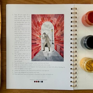 Puede incluir: Un cuaderno de bocetos abierto con encuadernaci&oacute;n en espiral, con una ilustraci&oacute;n en acuarela de Sherlock Holmes en un t&uacute;nel de ladrillos rojos. Se ven tres peque&ntilde;os botes de pintura y una paleta.