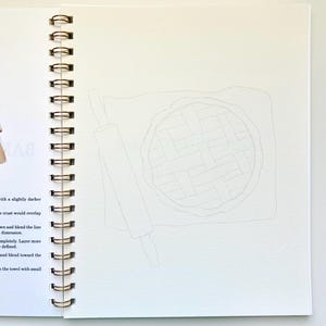 May include: A close-up of a blank page in a spiral bound sketchbook with a pencil drawing of a pie and a rolling pin. The pie is drawn with a lattice crust.