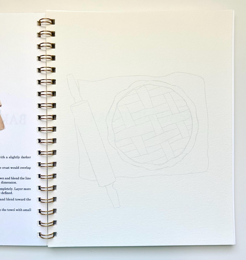 May include: A close-up of a blank page in a spiral bound sketchbook with a pencil drawing of a pie and a rolling pin. The pie is drawn with a lattice crust.