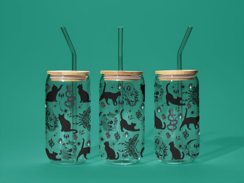 May include: Three glass tumblers with bamboo lids and glass straws. Each tumbler has a black cat and occult symbol pattern on a teal background. The design includes cats, skulls, and other mystical elements.