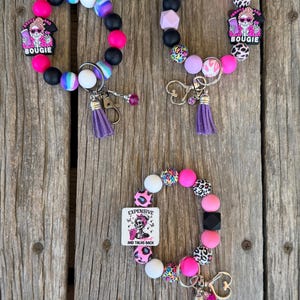 May include: Three beaded wristlet keychains with various bead designs, including leopard print, black, white, and pink. Each keychain features a charm with a skeleton graphic and the text "BOUGIE" or "EXPENSIVE AND TALKS BACK".