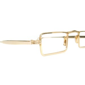 May include: Gold-toned eyeglasses with rectangular lenses and a bridge. The frames have a thin, delicate design, with a subtle curve at the top of the bridge. The temples are also gold and extend to the ear. The glasses are set against a white background.