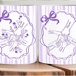 May include: White ceramic mug featuring a purple floral design with the word "Name" repeated. The design includes hands holding each other, a bow, and a striped background. The mug is on a wooden surface.