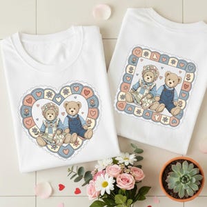 May include: Two white t-shirts with teddy bear graphics. One shirt features a heart-shaped frame with two bears, while the other has a square frame. The bears wear overalls and bonnets, surrounded by hearts and flowers.