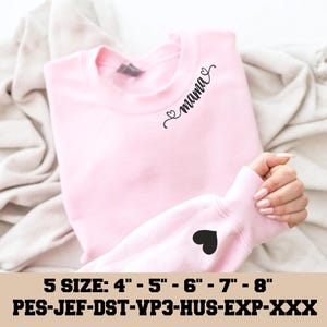 Puede incluir: Una sudadera rosa claro con la palabra "mama" en cursiva en la parte superior izquierda del pecho. Un corazón negro está en la manga izquierda. El texto "5 SIZE: 4" - 5" - 6" - 7" - 8"" está en la parte inferior.