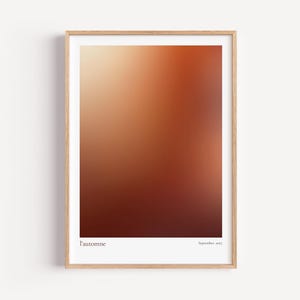 May include: A framed art print featuring a gradient of warm colors, transitioning from light beige at the top to deep brown at the bottom. The print is labeled "l'automne" and "September 2021". The frame is made of light-colored wood.