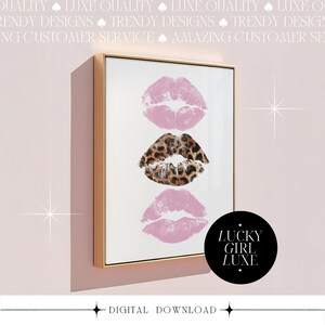 May include: A framed print featuring three lip prints: two in pink and one in a leopard print pattern. The artwork is in a gold frame and includes the text "LUCKY GIRL LUXE" on a black circle. The words "DIGITAL DOWNLOAD" are at the bottom.