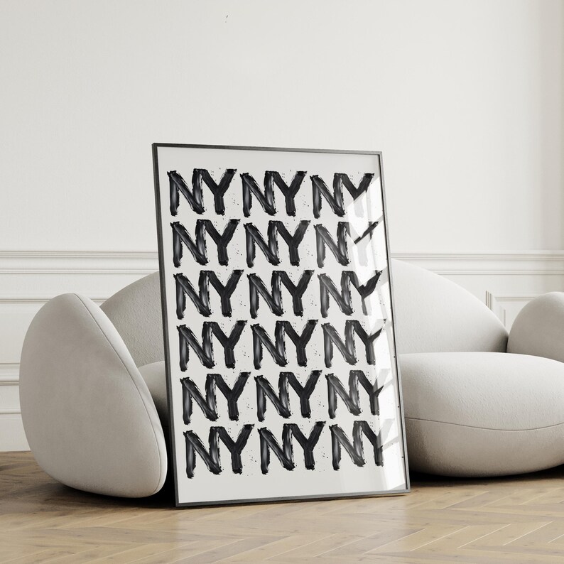 May include: Black and white art print featuring a repeating pattern of the letters NY. The letters are stylized in a bold, brushstroke font, creating a textured effect. The print is framed in a simple black frame and is displayed against a minimalist white background. The overall style is modern and graphic, suitable for contemporary interior design.