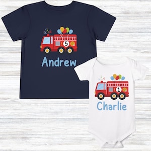May include: Navy blue t-shirt and white babygrow featuring a red fire engine design with balloons. The t-shirt has the name "Andrew" and the number "5". The babygrow has the name "Charlie" and the number "1".