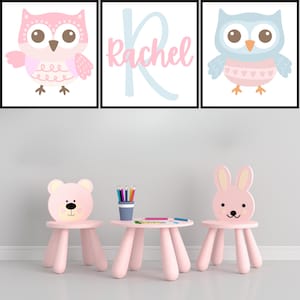 Puede incluir: Un juego de mesa y sillas para niños de color rosa con diseño de oso y conejo. La mesa tiene cuatro patas y una tapa redonda. Las sillas tienen cuatro patas y un respaldo con la cara de un oso o un conejo. Hay tres impresiones enmarcadas en la pared detrás de la mesa y las sillas. Las impresiones muestran búhos y el nombre "Rachel".