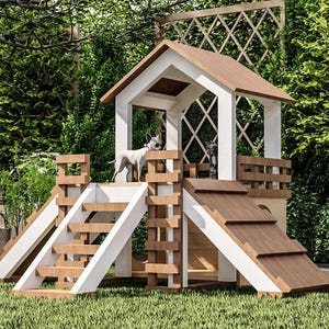 May include: A wooden dog playhouse with a white and brown color scheme. The structure includes a small house, stairs, and a ramp, all set on a grassy lawn. A small dog stands on the playhouse, with lush greenery in the background.