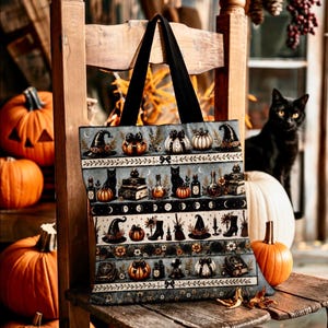 May include: A tote bag featuring a repeating horizontal pattern of Halloween-themed illustrations including black cats, pumpkins, witch hats, potion bottles, books, and moon phases on a dark gray background with two black fabric shoulder straps.