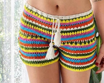 Könnte beinhalten: Bunte Häkelshorts mit Kordelzug und Quasten. Die Shorts weisen horizontale Streifen in verschiedenen Farben auf, darunter Gelb, Orange, Blau und Grün. Bund und Kanten sind mit weißer Häkelarbeit versehen.