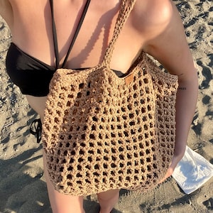 May include: A white ceramic mug with a black handle and the text "But First, Coffee" in a bold, black font. The mug is set against a blurred background, suggesting a cozy setting.