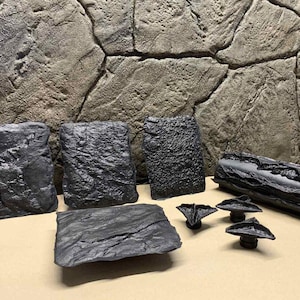 May include: A set of black textured stone-like molds for creating concrete or resin crafts. The set includes five flat molds, one log mold, and three small molds shaped like a leaf.