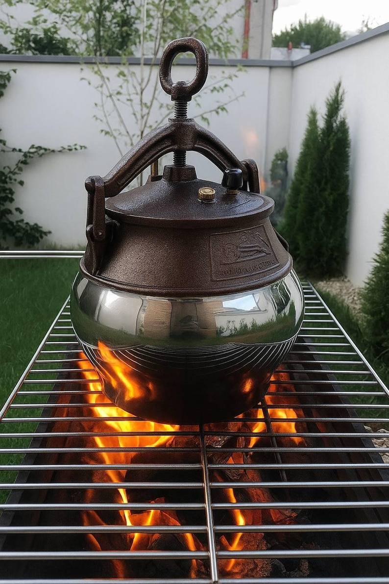 May include: A brown and silver pressure cooker sits on a metal grill over a fire. The cooker has a rounded base and a dark brown lid with a handle. Flames from the fire are visible beneath the grill, creating a warm, inviting scene.