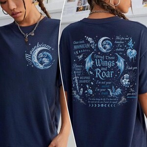 May include: A navy blue short-sleeve t-shirt featuring a front graphic of a crescent moon and dragon with the text Moonbeam. The back displays a large graphic with a dragon, wings, and text including Spread Those Wings and Roar.