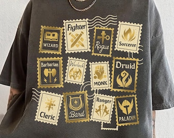 Puede incluir: Camiseta gris oscuro con diseños de sellos postales dorados con nombres de clases de fantasía como "Fighter", "Wizard" y "Rogue". La camiseta tiene un aspecto vintage y el texto "Calendulastyle" está en la parte inferior.