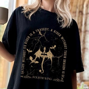 Puede incluir: Camiseta negra con un gr&aacute;fico dorado de un drag&oacute;n y el texto "A dragon without its rider is a tragedy. A rider without their dragon is dead. Fourth Wing."