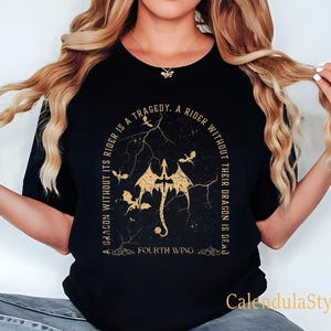 Puede incluir: Camiseta negra con un gr&aacute;fico dorado de un drag&oacute;n y el texto "A dragon without its rider is a tragedy. A rider without their dragon is dead. Fourth Wing."