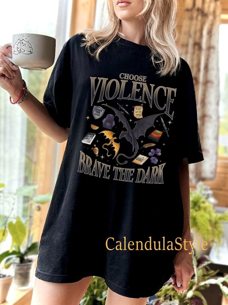 May include: Black t-shirt featuring a graphic print of a black dragon with gold accents. The text "Choose Violence Brave the Dark" is printed on the shirt.