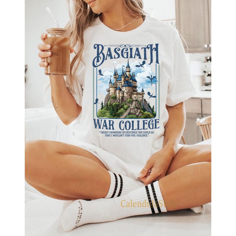 Op de afbeelding: Wit T-shirt met een afbeelding van een kasteel en de tekst "Basgiath War College" en de quote "Er is nergens ter wereld waar ik je niet zou vinden, geweld."