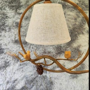 May include: A bronze-toned pendant light with a beige lampshade, featuring a branch design with small wooden birds and a pinecone. The light is suspended from a circular frame. The text "268 40cm" is visible, indicating a 40cm diameter.