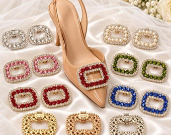 May include: A beige slingback high heel shoe adorned with a rectangular red crystal shoe clip. Surrounding the shoe are various rectangular shoe clips in colors including clear, pink, red, green, blue, gold, silver, and white pearl.
