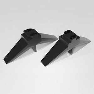 May include: Two black plastic TV stand legs with a triangular shape and a flat base. The legs have a raised rectangular section on top.