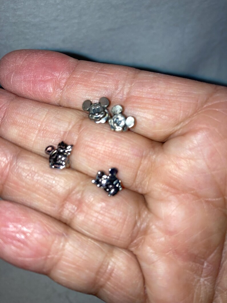 Puede incluir: Tres dijes de Mickey Mouse plateados, dos con orejas negras y uno con orejas plateadas.