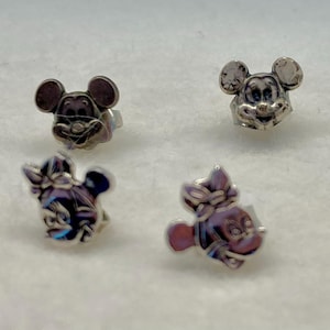 Puede incluir: Cuatro pendientes de bot&oacute;n plateados con los personajes de Mickey Mouse y Minnie Mouse. Los pendientes son peque&ntilde;os y delicados, perfectos para a&ntilde;adir un toque de magia Disney a cualquier atuendo.