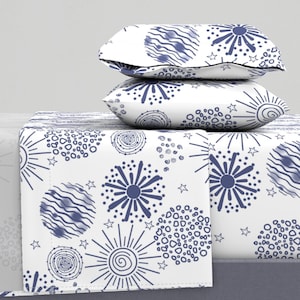 May include: A white bedding set with a blue and white pattern of stars, circles, and swirls. The bedding set includes a flat sheet, fitted sheet, and two pillowcases.