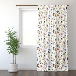 May include: White floral curtain featuring a pattern of colorful wildflowers in shades of pink, yellow, and blue. The curtain is hanging in front of a window, with a houseplant in a white pot to the left.