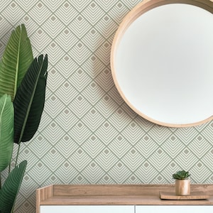 Puede incluir: Un papel tapiz geométrico beige y verde con un espejo redondo y un estante de madera con una pequeña planta en maceta en la parte superior.