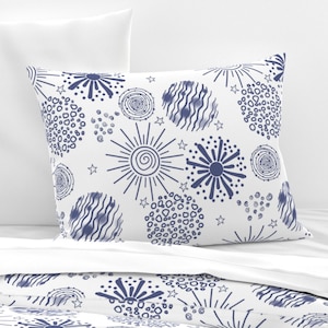 May include: A white pillowcase with a blue and white pattern of fireworks, stars, and circles. The pattern is repeated on the pillowcase and the pillow.