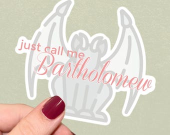 Op de afbeelding: Een gestanste sticker met een lichtgrijze illustratie van een waterspuwer met grote vleugels. Over de waterspuwer staat de roze tekst "just call me Bartholomew" in een combinatie van een schreefloos lettertype en een cursief lettertype.