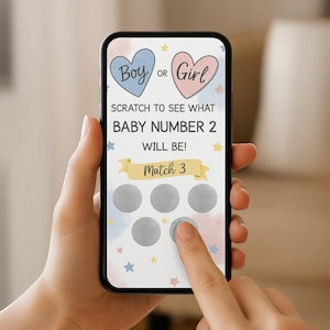 Peut inclure: Un &eacute;cran de smartphone affichant un jeu &agrave; gratter pour r&eacute;v&eacute;lation de genre avec des c&oelig;urs bleus et roses, des &eacute;toiles jaunes et le texte Boy or Girl, Scratch to see what baby number 2 will be, et Match 3 au-dessus de cinq zones &agrave; gratter.